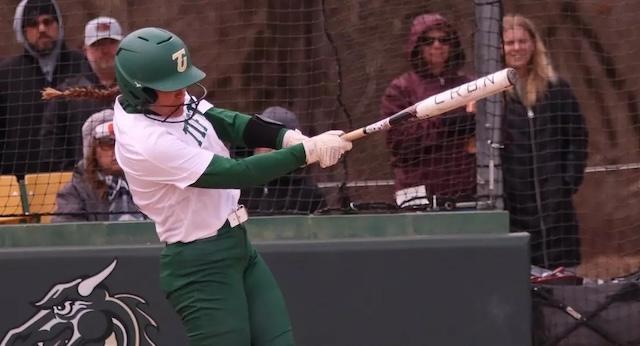 A Tiffin softball player in a white jersey blasts a home run. 